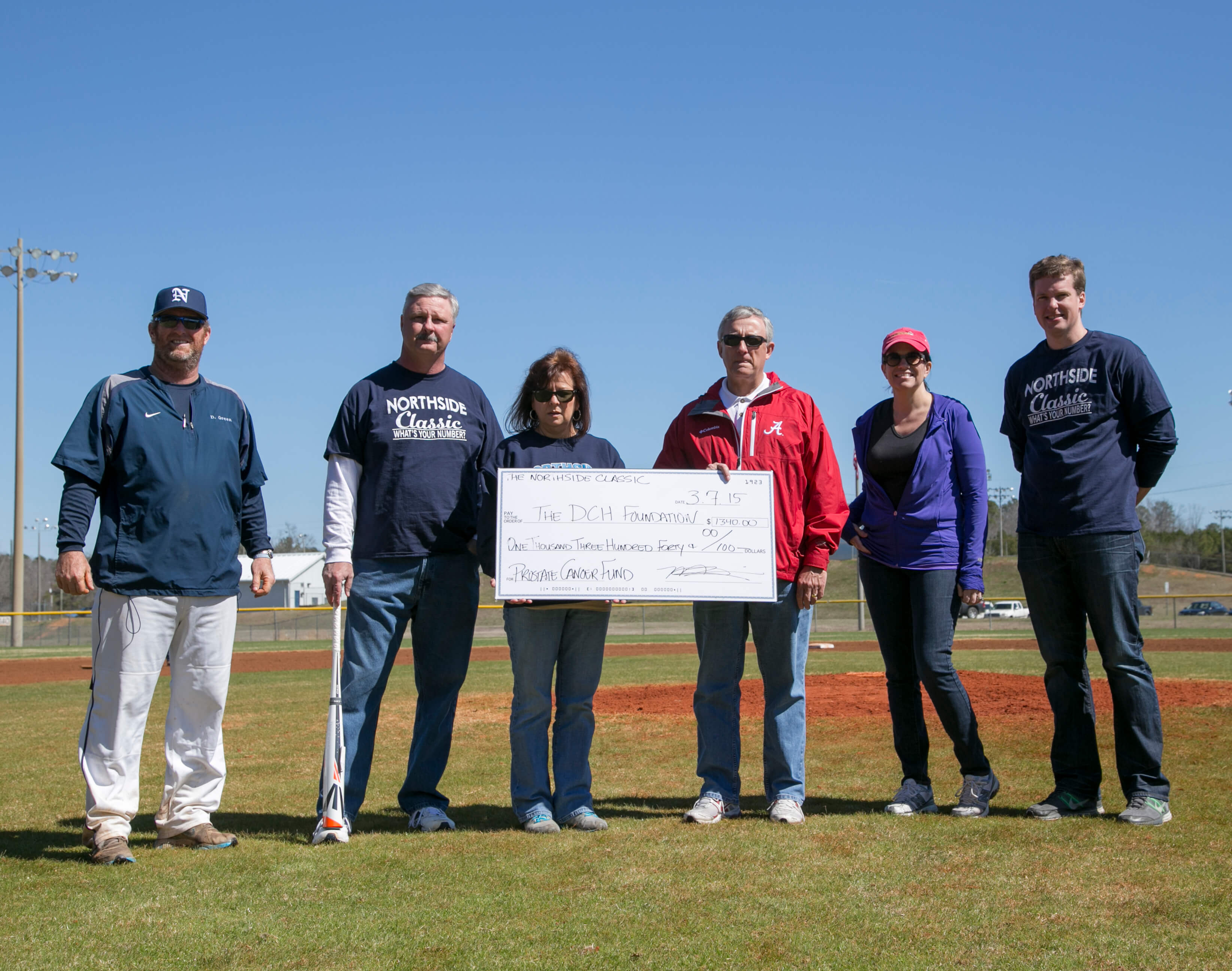 6 people standing with a large check
